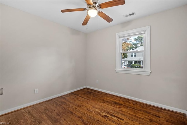 spare room with a ceiling fan, visible vents, baseboards, and wood finished floors