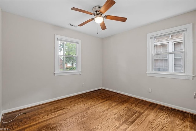 unfurnished room with a ceiling fan, baseboards, visible vents, and wood finished floors