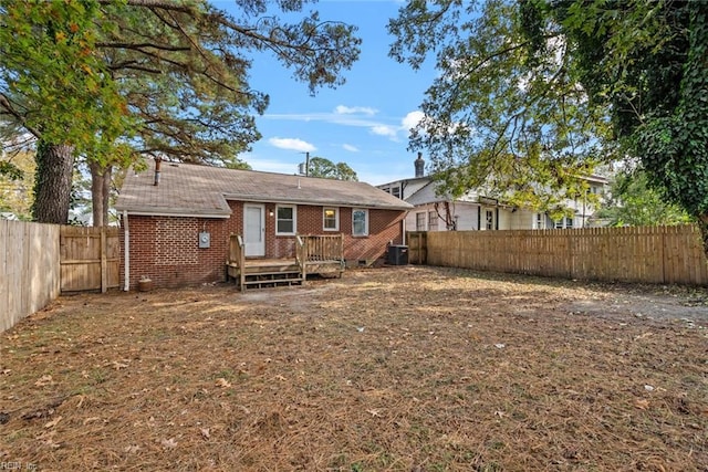 rear view of property featuring a deck, brick siding, cooling unit, and a fenced backyard