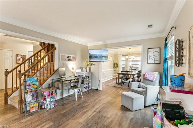 living area featuring a notable chandelier, wood finished floors, visible vents, ornamental molding, and stairway