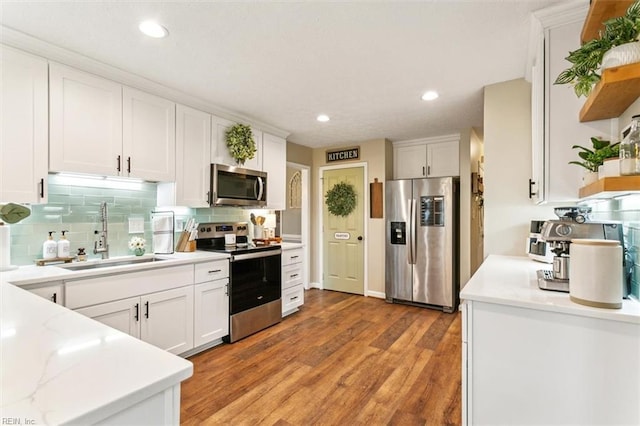 kitchen featuring appliances with stainless steel finishes, light wood-type flooring, white cabinets, and a sink