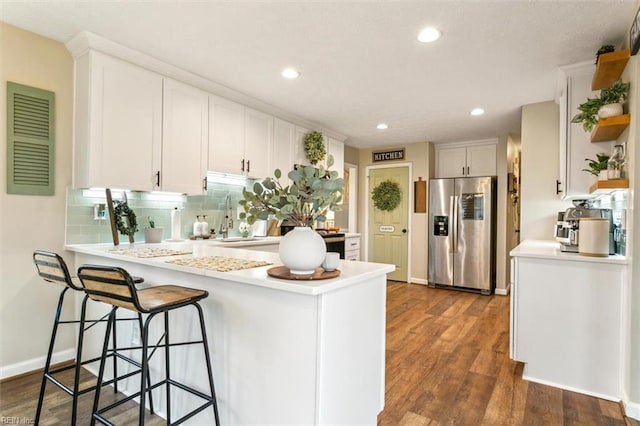 kitchen featuring white cabinets, a peninsula, and stainless steel fridge with ice dispenser