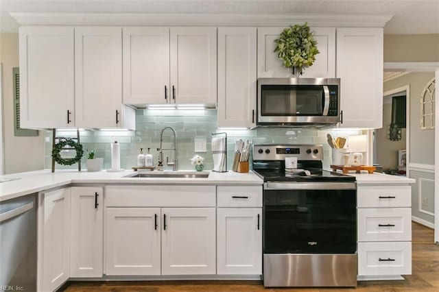 kitchen featuring white cabinets, decorative backsplash, stainless steel appliances, light countertops, and a sink