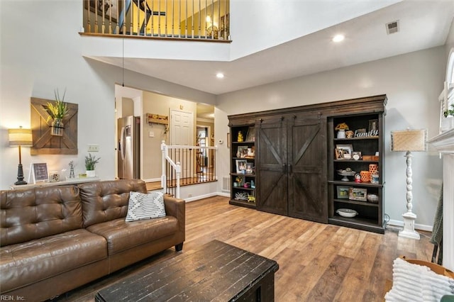 living room with recessed lighting, visible vents, baseboards, and wood finished floors