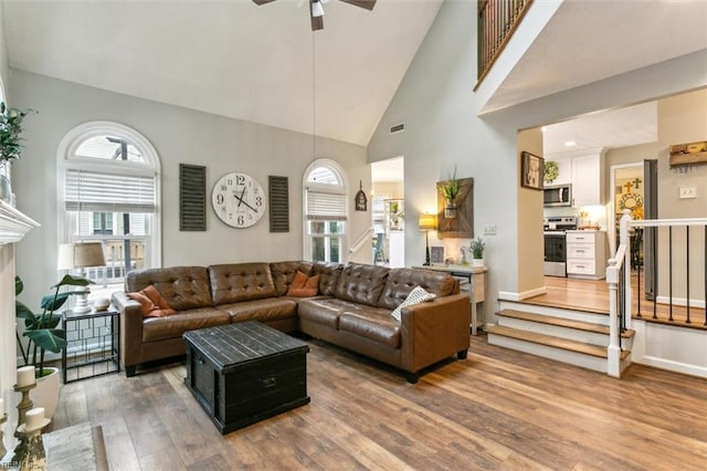 living room featuring high vaulted ceiling, visible vents, plenty of natural light, and wood finished floors