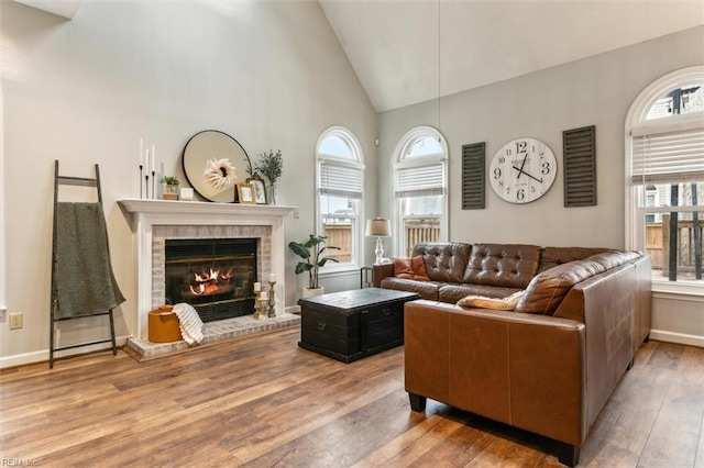 living room with high vaulted ceiling, a fireplace, plenty of natural light, and wood finished floors