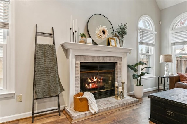 sitting room with a brick fireplace, baseboards, and wood finished floors