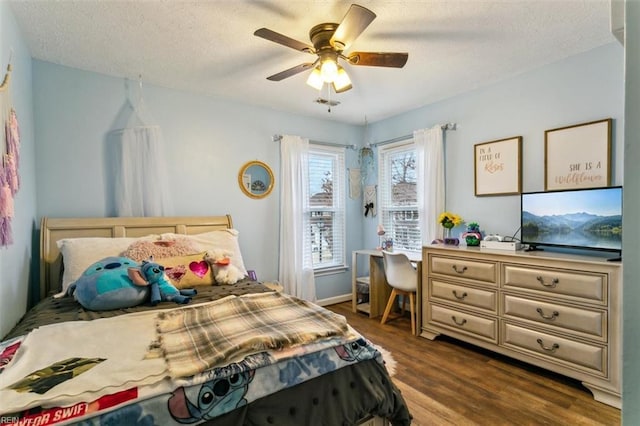 bedroom with a textured ceiling, a ceiling fan, and dark wood-type flooring