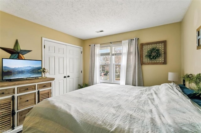 bedroom featuring a textured ceiling, visible vents, and a closet