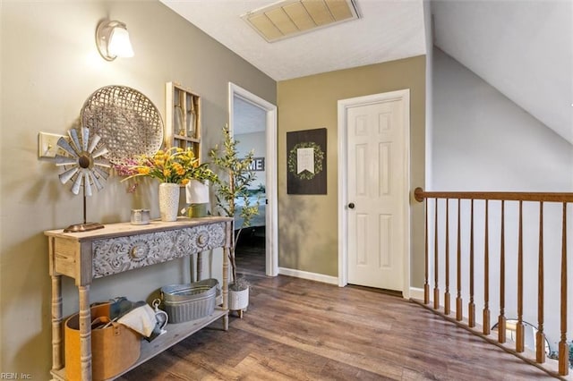 hall featuring baseboards, visible vents, and wood finished floors