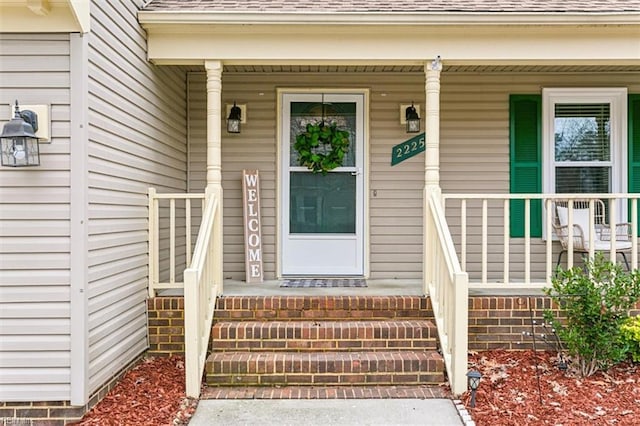 property entrance featuring covered porch and roof with shingles