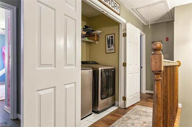 laundry area featuring laundry area, attic access, baseboards, wood finished floors, and washing machine and dryer