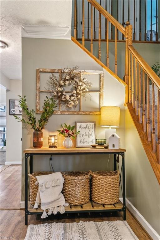 details with a textured ceiling, ornamental molding, wood finished floors, and baseboards