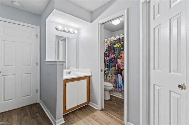 bathroom with toilet, baseboards, wood finished floors, and vanity