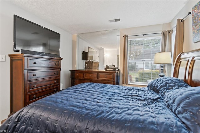 bedroom with a textured ceiling, multiple windows, and visible vents