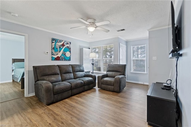 living room with ornamental molding, ceiling fan, a textured ceiling, and wood finished floors