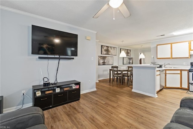 living area with visible vents, baseboards, a ceiling fan, light wood-style flooring, and crown molding