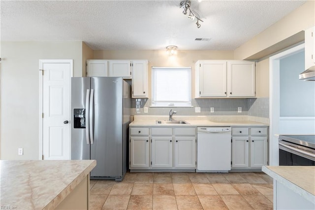 kitchen with a textured ceiling, stainless steel appliances, a sink, light countertops, and tasteful backsplash