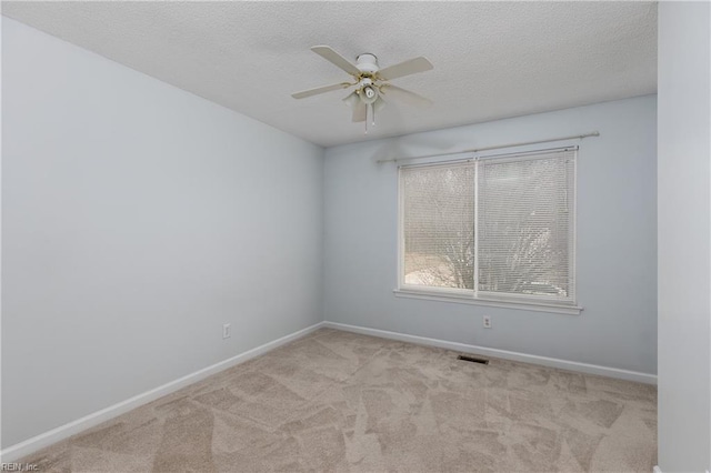 carpeted empty room with visible vents, ceiling fan, a textured ceiling, and baseboards