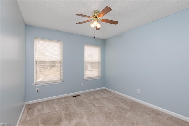 spare room with ceiling fan, a textured ceiling, visible vents, baseboards, and carpet