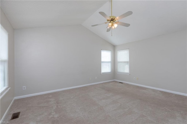 carpeted empty room with vaulted ceiling, ceiling fan, visible vents, and baseboards