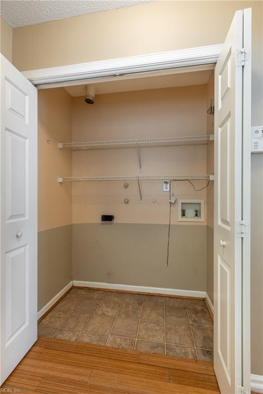 clothes washing area with laundry area, wood finished floors, hookup for a washing machine, and baseboards