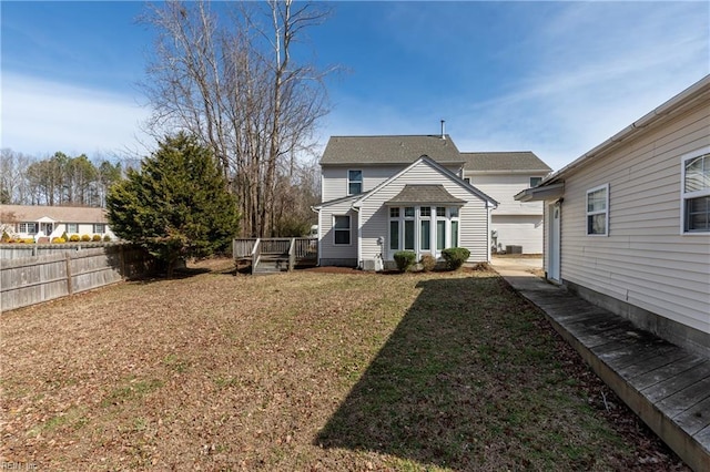 rear view of property featuring a yard, fence, and a deck