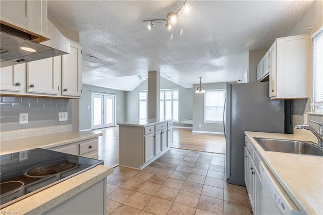 kitchen with dishwasher, light countertops, a sink, and under cabinet range hood