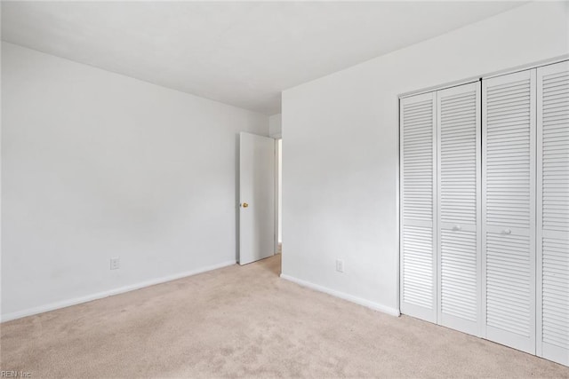 unfurnished bedroom featuring light carpet, baseboards, and a closet