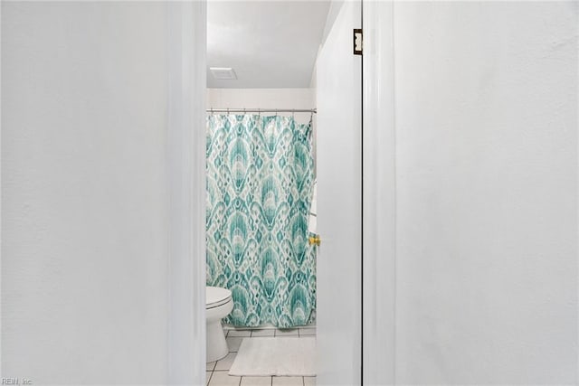 bathroom featuring tile patterned flooring, curtained shower, and toilet