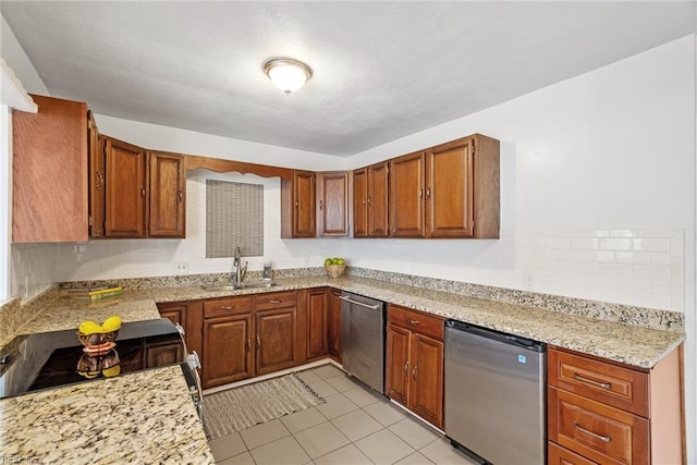 kitchen featuring brown cabinetry, refrigerator, a sink, dishwasher, and tasteful backsplash