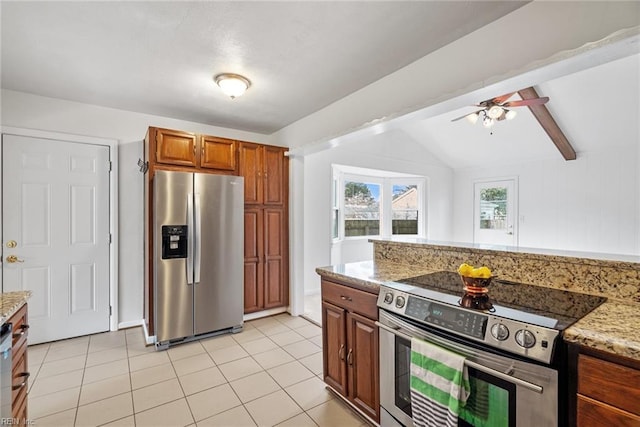 kitchen with brown cabinets, lofted ceiling with beams, appliances with stainless steel finishes, light tile patterned flooring, and light stone countertops