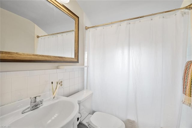 bathroom with curtained shower, tile walls, toilet, and a sink