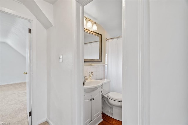 full bath with toilet, vanity, and lofted ceiling