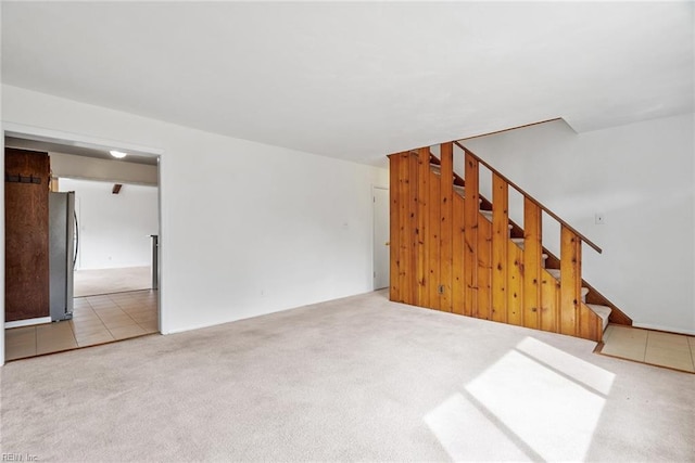 unfurnished living room featuring stairs, wooden walls, and carpet floors