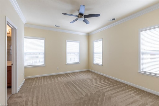 spare room featuring ornamental molding, plenty of natural light, visible vents, and light colored carpet