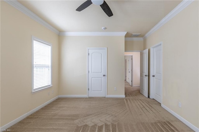 unfurnished bedroom featuring carpet floors, a ceiling fan, baseboards, and crown molding