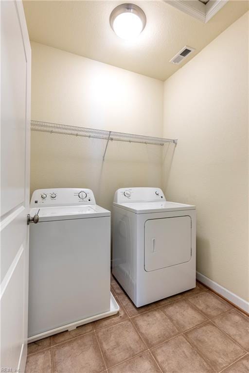 laundry area featuring washing machine and clothes dryer, light tile patterned floors, visible vents, laundry area, and baseboards