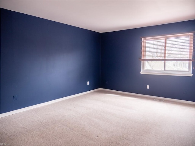 spare room featuring carpet flooring and baseboards