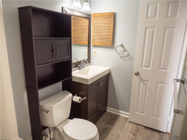 half bath featuring toilet, baseboards, wood finished floors, and vanity