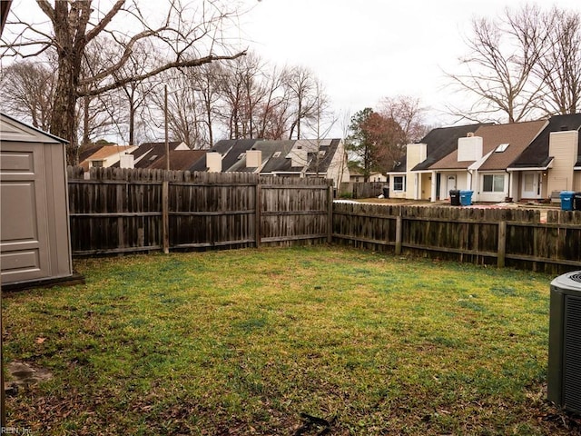 view of yard featuring an outbuilding, a storage shed, central AC unit, a residential view, and a fenced backyard