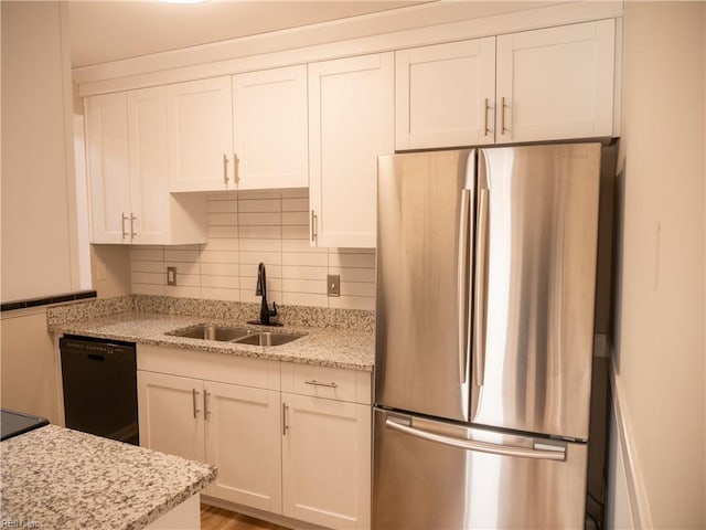 kitchen with tasteful backsplash, freestanding refrigerator, white cabinetry, a sink, and dishwasher