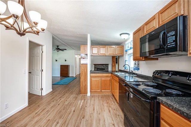 kitchen featuring a fireplace, light wood-style flooring, a ceiling fan, a sink, and black appliances