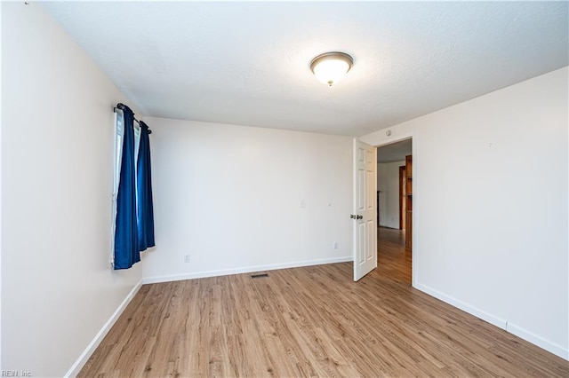 unfurnished room with baseboards, visible vents, and light wood finished floors