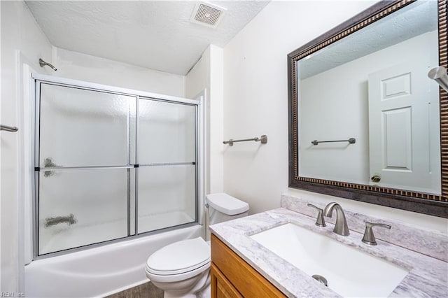 bathroom featuring a textured ceiling, enclosed tub / shower combo, toilet, vanity, and visible vents