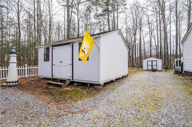 view of shed featuring gravel driveway and fence