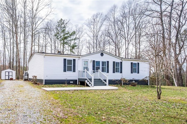 manufactured / mobile home with a front yard, gravel driveway, an outdoor structure, and a storage shed