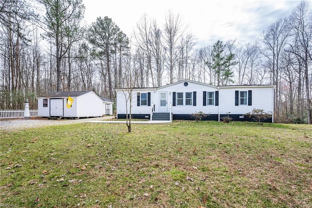 manufactured / mobile home featuring an outbuilding, fence, and a front lawn