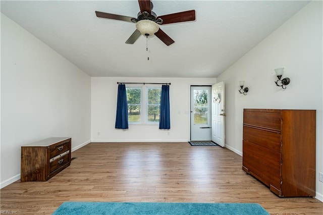 interior space featuring lofted ceiling, ceiling fan, baseboards, and wood finished floors