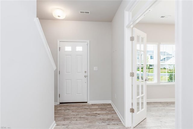 foyer featuring light wood-type flooring, visible vents, and baseboards